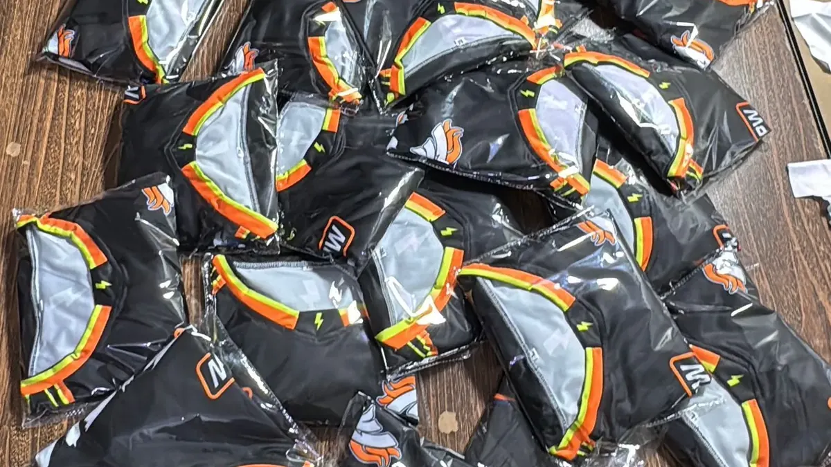 Finished black sports garments folded and sealed in individual clear bags on a table, ready to be packed for shipping