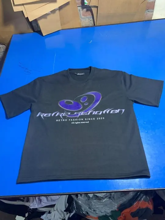 Custom black tee with a metallic chrome-effect chest print, flat lay