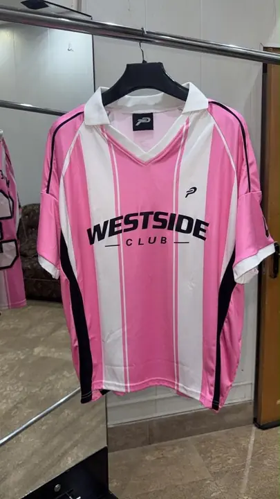Custom pink and white striped club jersey with black side panels, on a hanger