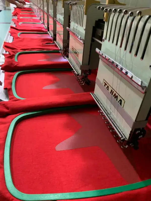 Multi-head embroidery machines stitching logos onto red garments