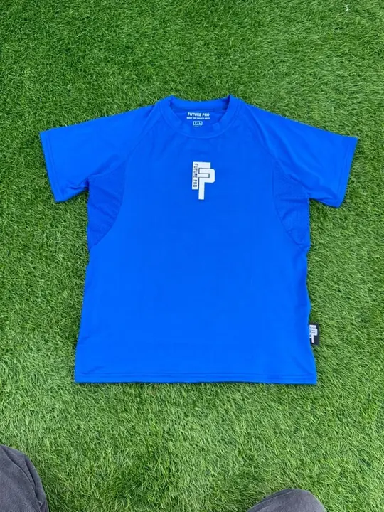 Custom royal blue performance tee with a printed chest logo, laid on grass