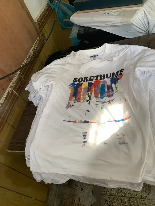 Custom screen-printed graphic t-shirt, white colorway, "Sore Thumb" private-label streetwear brand, front