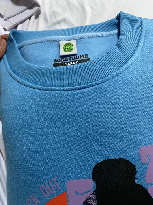 Custom light-blue crewneck sweatshirt with a printed graphic and neck label, close-up