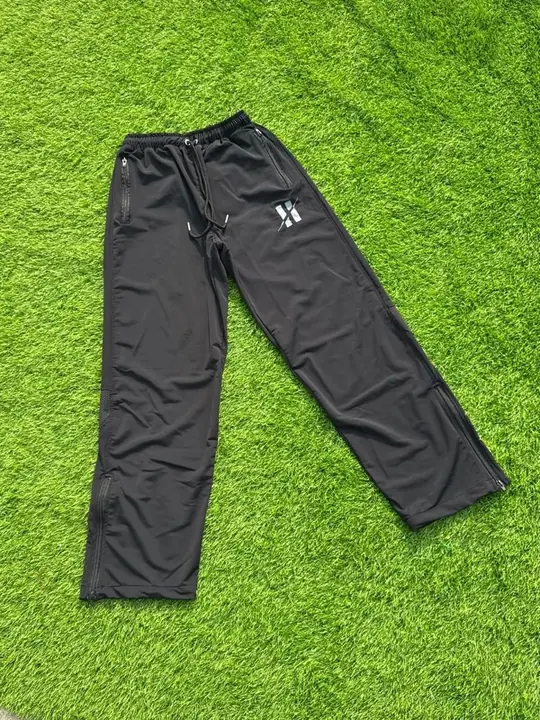 Custom black track pants with zipped hems, laid flat