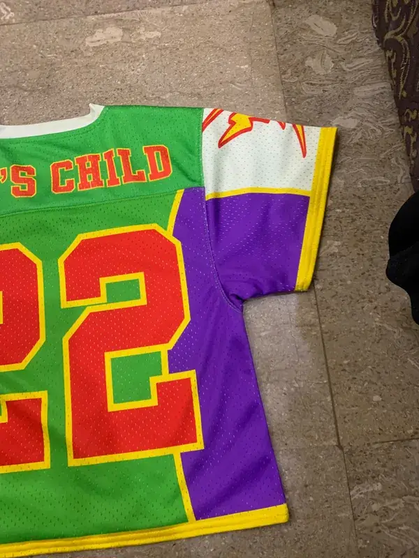 Custom sublimated lacrosse jersey, green purple and yellow, numbered "22" with team wordmark, front flat lay